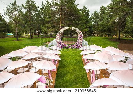 Outdoor wedding ceremony with umbrellas in the forest.