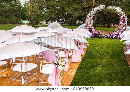 Outdoor wedding ceremony with umbrellas in the forest.