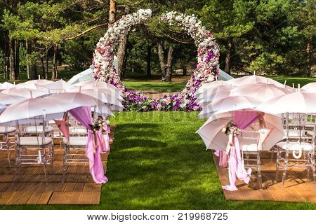 Outdoor wedding ceremony with umbrellas in the forest.