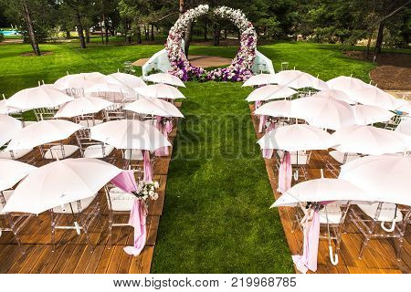 Outdoor wedding ceremony with umbrellas in the forest.