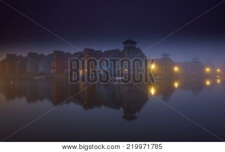 Colourful wooden housings in a misty dawn at the Reitdiephaven in Groningen, The Netherlands