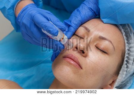 Cosmetic treatment by injection in the clinic. Use of a dermal injector to stimulate the skin. A woman receives injections of a placental-peptide serum