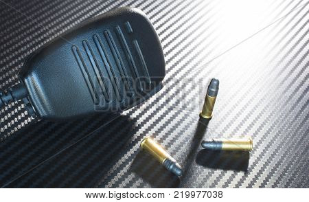 Police microphone with three rim fire cartridges on a dark background
