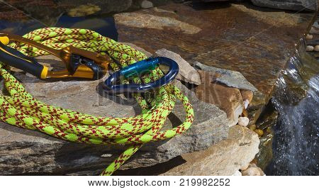 Yellow climing rope with a equipment next to a small cascade