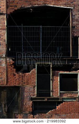 destroyed red brick wall with fences and doors