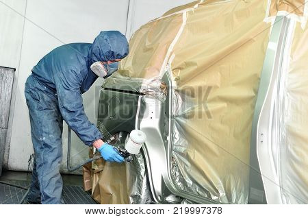 Professional car painter spraying a silber car.
