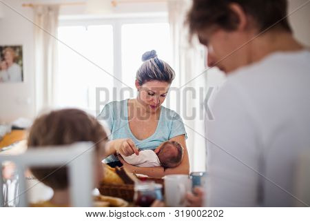 Young Parents With Newborn Baby And Small Toddler Son At Home.