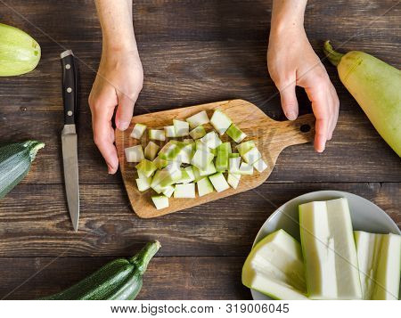 Zucchini Harvest. Woman Slices Zucchini Cubes For Freezing On Wooden Table. Farm Organic Zucchini Ha
