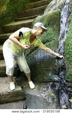 Woman Washing Hand With Water From Stream