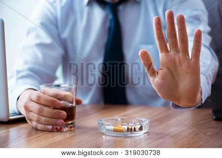 Male employee drinking alcohol and smoking cigarettes at workpla