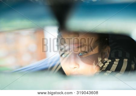 Beautiful Woman Driver Reflecting In The Rear View Mirror. Driving Her Car Concept. Artistic Shot Wi