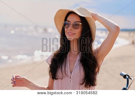 Portrait Of Beautiful Smiling Girl In Sunglasses And Pink Dress At Calm Seaside.