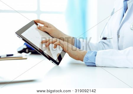 Doctor Working Table. Woman Physician Using Tablet Computer While Sitting In Hospital Office Close-u