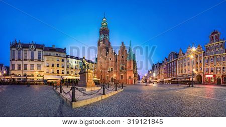 Panoramic View Of Rynek Square In Wroclaw, Poland With Gothic Town Hall And Monument At Dusk