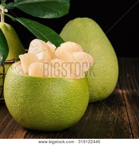 Fresh Peeled Pomelo, Grapefruit, Shaddock With Green Leaves On Dark Wooden Plank Table. Seasonal Fru