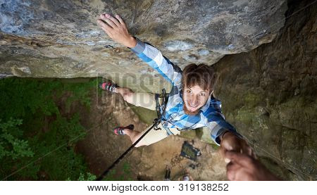 Man Climbing With Safety Harness And Rope Pulling Up His Hand. Man Helping His Friend To Climb On Cl