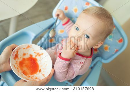 Adorable Cute Caucasian Blond Toddler Boy Eating Tasty Vegetable Soup In Chair At Kithcen Indoor. Mo