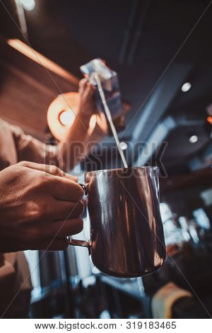 Talanted Barista Is Pouring Milk To The Jug For Latte Or Cappuchino At His Cafe.