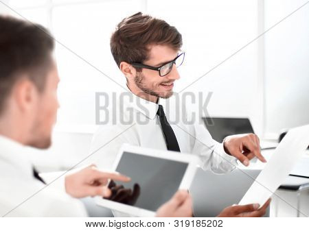 Team of two businessmen discussing new project using tablet and dokuments in the office.