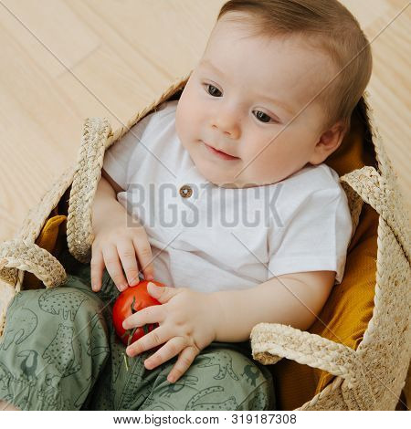 Infant Baby Is Sitting In A Woolven Like Bag