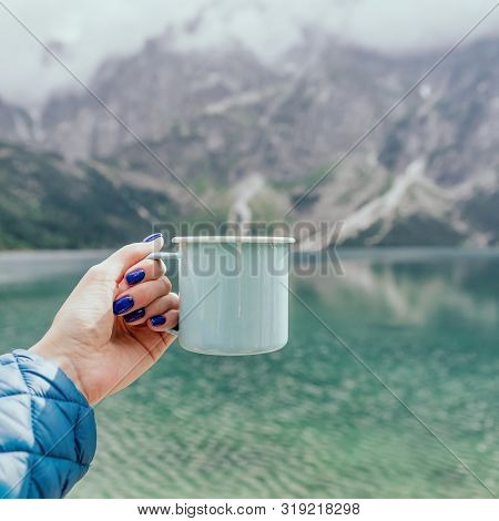 Female Hand Holding Mint Color Enamel Cup. Crystal Clear Lake And Mountains. Tatra National Park, Po