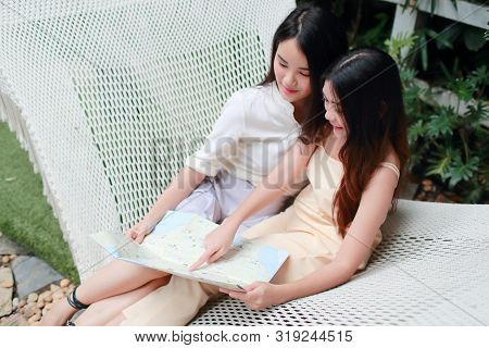 Young And Cute Asian Women Lying In A Hammock And Searching Location In A Map During Holiday