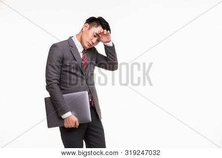 Handsome Asian Businessman Standing Putting Hand On Forehead And Holding Notebook Computer In His Ha