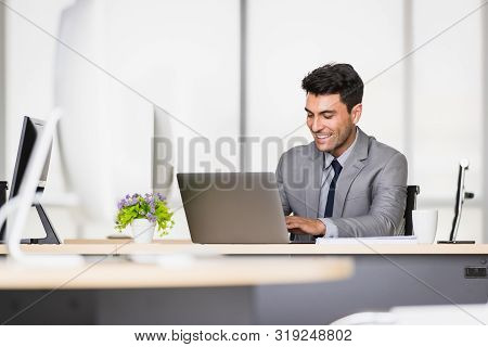 Handsome Caucasian Businessman Holding A Pen In His Hands, On A Table With A Notebook And A Coffee M