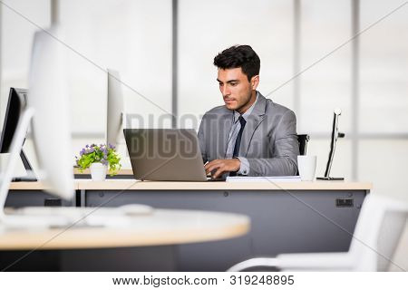 Handsome Caucasian Businessman Holding A Pen In His Hands, On A Table With A Notebook And A Coffee M