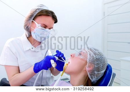 Dentist Hygienist Makes Ultrasonic Teeth Cleaning For Young Woman In Dentistry. Patient Visit Dentis