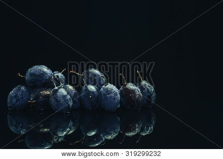 Beautiful Fresh Blue Pulms On A Black Glass Table And Dark Background.