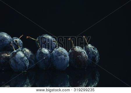 Beautiful Fresh Blue Pulms On A Black Glass Table And Dark Background.