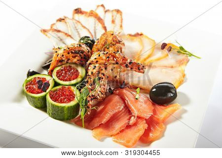Fish platter with pink salmon, grilled eel, oil fish balyk and red caviar on elegant restaurant plate isolated on white background. Exquisite serving thin slices of salted and dried delicious seafood