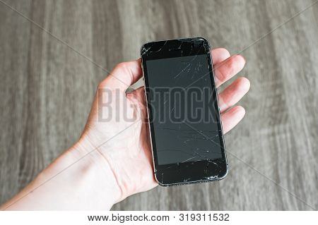 Broken Black Phone Screen In Hand On The Grey Background