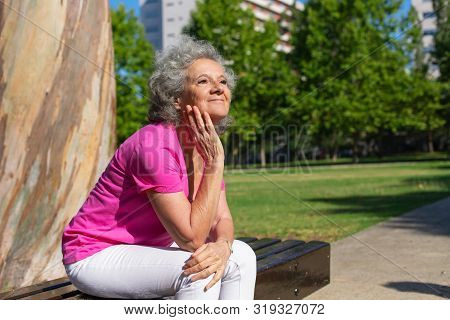 Joyful Old Lady Waiting Someone In City Park. Senior Grey Haired Woman In Casual Sitting On Bench Ou