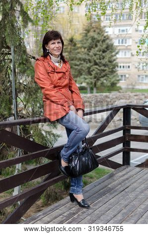 Portrait Of A Lonely Older Woman With A Beautiful Face, Smiling, Walking In The Park Waiting For The