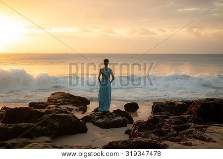 Woman Enjoying Sunset At The Beach. View From Back. Golden Sunset. Sunset Seascape. Bright Sunlight.