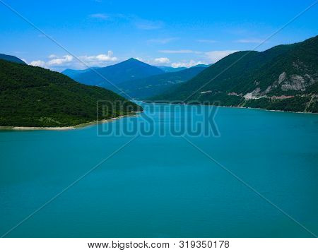 Beautiful Landscape Overlooking A Large Blue Lake In The Mountains Covered With Forest.