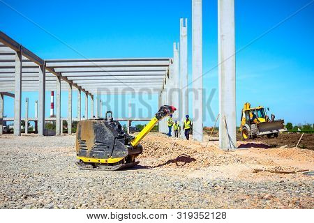 Used Plate Compactor, Vibratory Hammer, Jumping Jack Machine, Power Tool Placed In Shadow At Constru