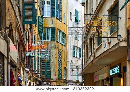 Genoa, Italy - July 06, 2019: Old street with signboards of shops and cafes in Genoa