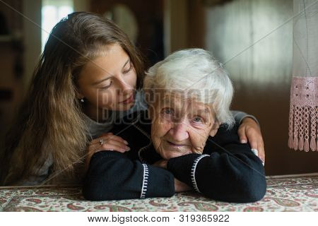 Portrait of elderly woman c beloved granddaughter in the house.