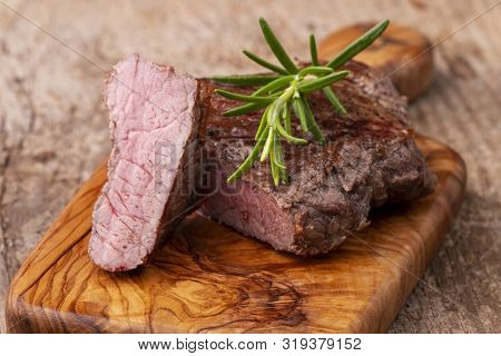 Closeup Of Grilled Steak On Wood With Rosemary