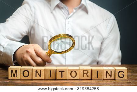 A Man With A Magnifying Glass Examines Word Monitoring. Verification And Control, Business Audit. In