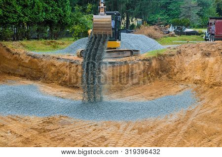 The Excavator Wheel During Backfilling Gravel Around The Foundation For A New Home Construction