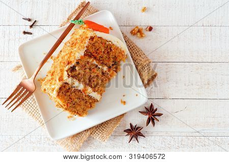 Slice Of Homemade Carrot Cake With Cream Cheese Frosting On A Plate. Top View Table Scene Over A Rus