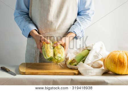 Woman Cook In Cotton Apron Holds Ripe Corn In Her Hands. Rustic Natural Style. The Concept Organic F