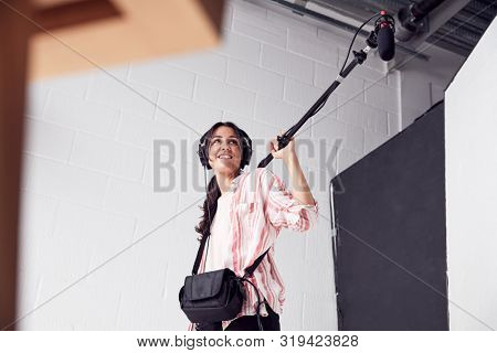 Female Sound Recordist Holding Microphone On Video Film Production In White Studio