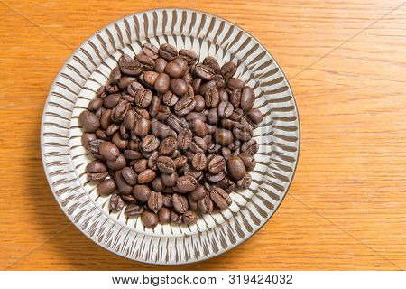 Coffee Beans On A Plate Placed On A Wooden Table.