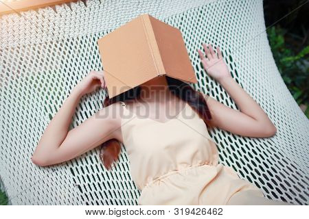 Young And Cute Asian Girl Lying In A Hammock With Book During Holiday