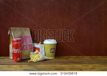 Mcdonalds Take Away Paper Bag And French Fries With Coca Cola Can On Wooden Table
